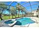 Inviting screened-in pool and spa with tropical landscaping and clear blue skies at 847 Orista Dr, Davenport, FL 33897