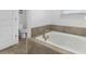 A luxurious soaking tub in a well-lit bathroom features neutral tiles and modern fixtures for relaxation at 9118 Sommerset Hills Dr, Davenport, FL 33896