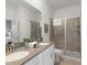 Modern bathroom featuring double sinks, a shower with glass doors, and neutral finishes at 9118 Sommerset Hills Dr, Davenport, FL 33896