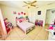 bedroom features a pink bed, tiled floors, and a ceiling fan, creating a whimsical and cozy space at 467 Martigues Drive, Kissimmee, FL 34759