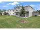 Large backyard featuring a covered patio, lush grass, and newly planted tree, great for outdoor living at 1027 Cloud Ridge Ct, Mount Dora, FL 32757