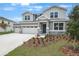 Two-story gray home with a three-car garage, stone accents, and landscaped front yard at 1027 Cloud Ridge Ct, Mount Dora, FL 32757