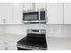 Close-up of stainless steel microwave and electric range with white subway tile backsplash at 1027 Cloud Ridge Ct, Mount Dora, FL 32757