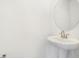 Clean powder room with a pedestal sink, round mirror, and minimalist design at 1027 Cloud Ridge Ct, Mount Dora, FL 32757