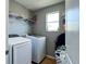 A fully equipped laundry room with washer, dryer, shelving, and natural light from a window at 1043 Tourmaline Dr, Kissimmee, FL 34746