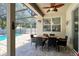View of an outdoor dining area with a ceiling fan overlooking a screened-in pool at 1043 Tourmaline Dr, Kissimmee, FL 34746