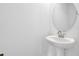 A pedestal sink and round mirror in a minimalist bathroom, featuring bright white walls and sleek fixtures at 1051 Cloud Ridge Ct, Mount Dora, FL 32757