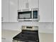 Close-up of a kitchen featuring stainless steel appliances, white subway tile backsplash and sleek white cabinets at 1051 Cloud Ridge Ct, Mount Dora, FL 32757