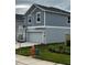 Side view of a gray two-story home with a two-car garage and neatly trimmed landscaping at 1053 Waterfall Blvd, Davenport, FL 33837