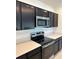 Modern kitchen with stainless steel oven, microwave, black cabinets, and quartz countertops at 1053 Waterfall Blvd, Davenport, FL 33837