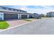 A long view of townhome garages featuring brick paver driveway, green grass and landscaping, and a parked car at 12190 Plumpton Dr, Winter Garden, FL 34787
