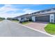 A long view of townhome garages featuring brick paver driveway, green grass and landscaping, and a parked car at 12190 Plumpton Dr, Winter Garden, FL 34787