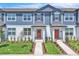 Charming two-story townhomes with blue siding, coral doors, white trim, and landscaped front yards with walkways at 12190 Plumpton Dr, Winter Garden, FL 34787