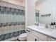 Well-lit bathroom features a shower with a patterned curtain and a modern sink at 140 Trinity Ridge Cir, Davenport, FL 33897