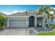 Inviting home with a beautifully landscaped front, paver driveway, gray exterior, and a vibrant turquoise front door at 140 Trinity Ridge Cir, Davenport, FL 33897