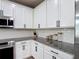 Close-up of kitchen with granite countertops, white cabinets, subway tile backsplash, and stainless steel appliances at 140 Trinity Ridge Cir, Davenport, FL 33897