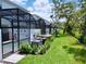 Backyard featuring screened-in patios, well-maintained landscaping, and lush green lawn at 1425 Serendipity Ln, Clermont, FL 34714