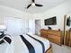 Bedroom showcasing a wood dresser, TV, closet, ceiling fan, and modern decor at 1425 Serendipity Ln, Clermont, FL 34714