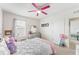 This bedroom has a window, carpet flooring, ceiling fan, dresser and a bed with pink accents at 1490 Olive Ct, St Cloud, FL 34771