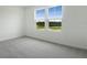 Bright bedroom with two large windows, plush carpeting, and neutral walls at 232 Flag Lilly Ln, Umatilla, FL 32784