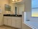 Bathroom featuring double sinks, granite counters, and a tiled bathtub at 240 Steamboat Blvd, Davenport, FL 33897