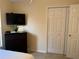 Bedroom features a dark wood dresser, mounted tv, neutral walls, and closet with paneled doors at 240 Steamboat Blvd, Davenport, FL 33897