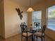Cozy dining area with a glass table, decorative dragonfly, and natural light from a window at 240 Steamboat Blvd, Davenport, FL 33897