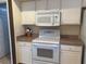 Close up of a white oven and microwave set into white cabinets with neutral counter tops at 240 Steamboat Blvd, Davenport, FL 33897