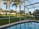 Screened in backyard pool with views of the manicured landscaping and distant neighborhood homes at 240 Steamboat Blvd, Davenport, FL 33897