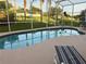 Screened in backyard pool with surrounding landscaping and nearby lounge chairs at 240 Steamboat Blvd, Davenport, FL 33897