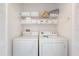 Bright laundry room featuring a stacked washer and dryer with convenient shelving for storage at 2438 Sweetwater Club Cir # 50, Kissimmee, FL 34746