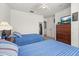 Bedroom with blue striped bedding, neutral walls, and a wood dresser with TV at 2620 Lodi Cir # 103, Kissimmee, FL 34746