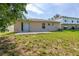 Backyard view with sliding glass door, patio, mature trees and lush green grass at 265 Curtis Ave, Groveland, FL 34736