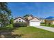 Inviting single-story home with a lush green lawn, mature shrubbery, and a two-car garage offering serene suburban living at 265 Curtis Ave, Groveland, FL 34736