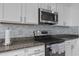Close-up of a modern kitchen with stainless steel appliances, granite countertops, and white cabinets at 2715 Barclay Ln, Kissimmee, FL 34743