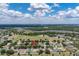 Wide aerial view showcases residential neighborhood, green spaces, scattered trees on a sunny day at 3125 Samosa Hill Cir, Clermont, FL 34714