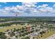 Wide aerial view showcases neighborhood near Walt Disney World, green spaces, scattered trees under blue skies at 3125 Samosa Hill Cir, Clermont, FL 34714