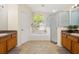 Bright bathroom featuring a soaking tub, shower, and double vanities with wood cabinets at 3125 Samosa Hill Cir, Clermont, FL 34714