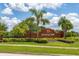 Brick 'Orange Tree' community sign bordered by vibrant palm trees and manicured landscaping at 3125 Samosa Hill Cir, Clermont, FL 34714