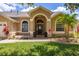 Welcoming front entrance featuring a charming archway, lush landscaping, and a covered porch at 3125 Samosa Hill Cir, Clermont, FL 34714