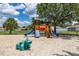 Community playground with colorful play structure, slides, and a dinosaur spring rider set in sand at 3125 Samosa Hill Cir, Clermont, FL 34714