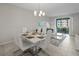 Bright dining area features a white table set for six under a modern chandelier, adjacent to a living area with balcony access at 3150 Paradox Cir # 104, Kissimmee, FL 34746
