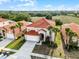 Aerial view of the home featuring a red tile roof, green lawn, palm trees, and view of the wooded area in the back at 321 Rosso Dr, Davenport, FL 33837
