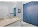 Cozy bathroom featuring a single sink vanity, framed mirror, and a shower with a blue curtain at 321 Rosso Dr, Davenport, FL 33837