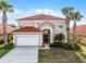 Stunning two-story home with a red tile roof, palm trees, and a two-car garage at 321 Rosso Dr, Davenport, FL 33837