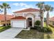 Charming two-story home featuring a red tile roof, an attached two car garage, and mature palm trees at 321 Rosso Dr, Davenport, FL 33837