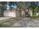 Tan single-Gathering home featuring a two-car garage, neutral paint scheme, and landscaping with mature trees at 3370 Cypress Point Cir, St Cloud, FL 34772