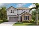 Charming two-story home featuring a stone facade, gray siding, well-manicured lawn, and an attached two-car garage at 3781 Deer Ridge Dr, Mount Dora, FL 32757