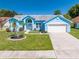 Bright blue home featuring a well-maintained lawn, a two-car garage, and manicured landscaping at 3893 Blackberry Cir, St Cloud, FL 34769