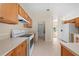 Open kitchen with white appliances and wooden cabinets, with a view of the living room at 3893 Blackberry Cir, St Cloud, FL 34769